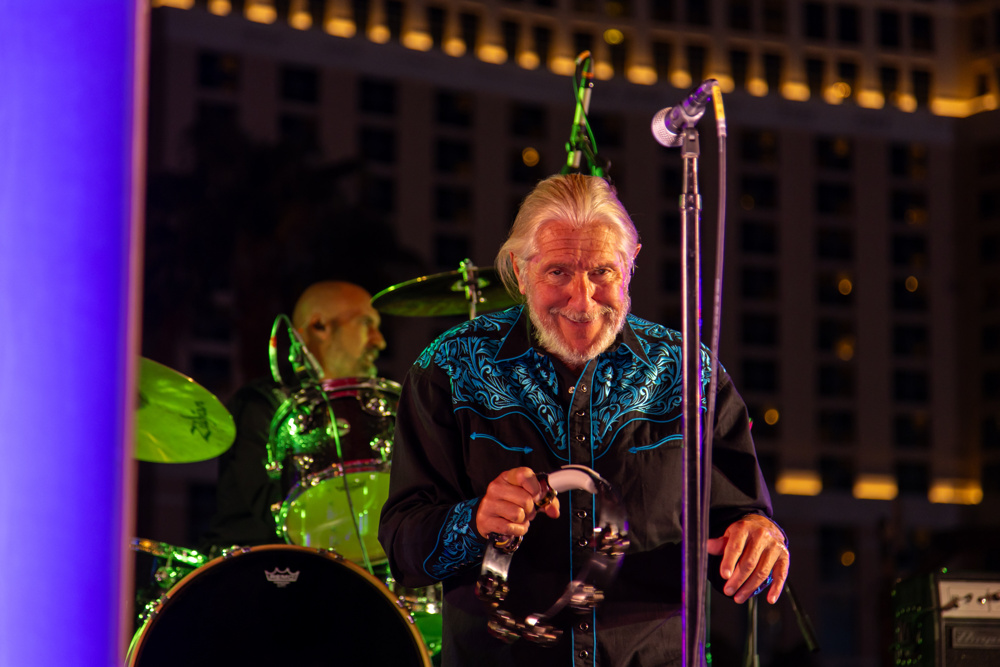 A singer performs with a live band at an outdoor evening event